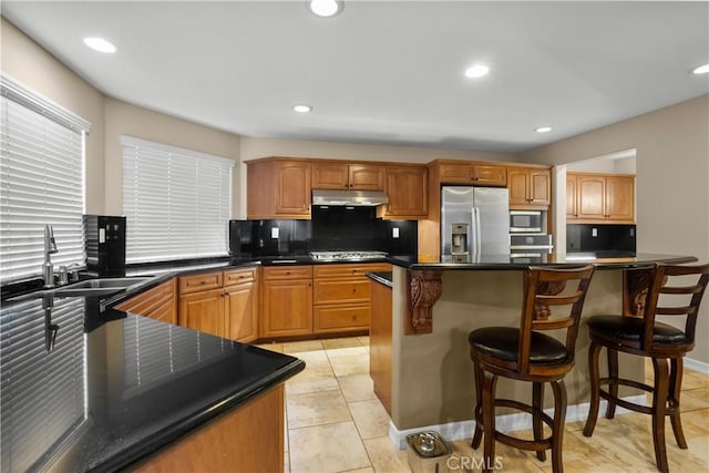 kitchen featuring a breakfast bar, sink, appliances with stainless steel finishes, tasteful backsplash, and a kitchen island