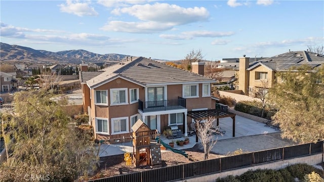 view of front of house with a playground, a pergola, a mountain view, and a balcony