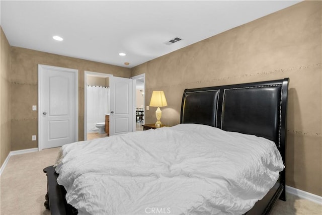 bedroom with light colored carpet and ensuite bath