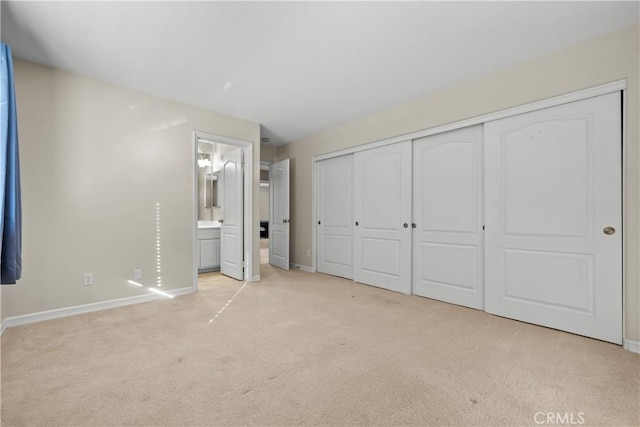 unfurnished bedroom featuring connected bathroom, a closet, and light colored carpet