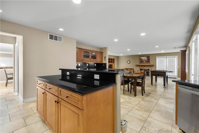 kitchen with a fireplace, dishwasher, a center island, and light tile patterned floors