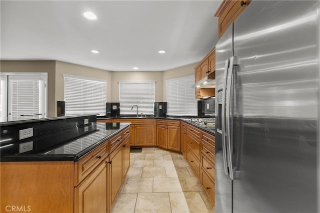 kitchen with dark stone countertops, stainless steel fridge, and sink