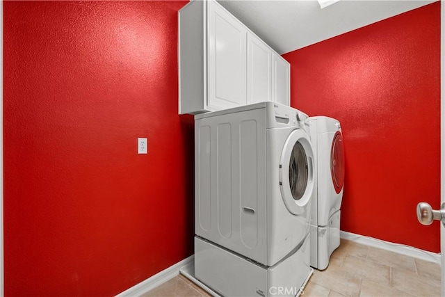 laundry area with washing machine and clothes dryer and cabinets