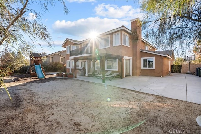 rear view of property with a patio, a playground, and a balcony