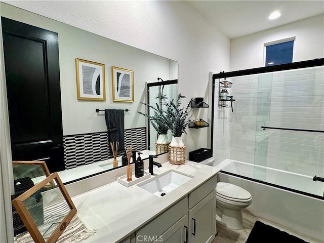 full bathroom featuring toilet, vanity, and shower / bath combination with glass door