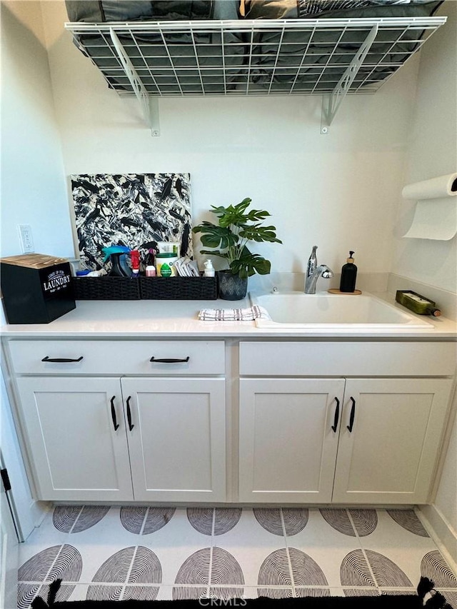 interior space featuring light tile patterned floors, sink, and white cabinetry