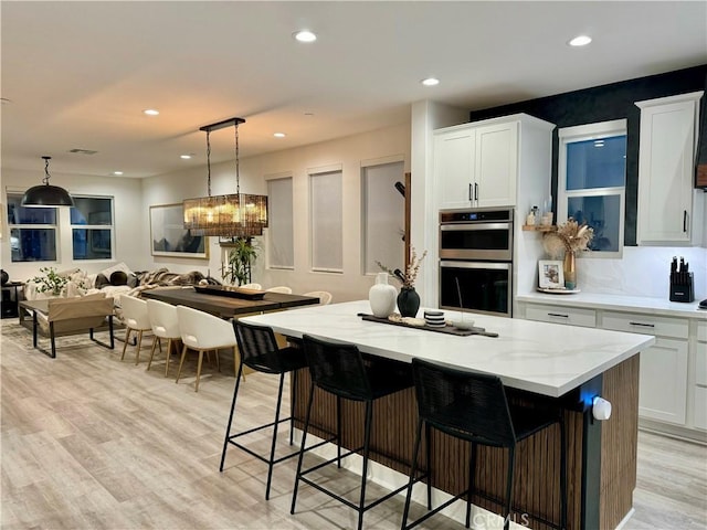 kitchen with white cabinetry, pendant lighting, a center island, and stainless steel double oven