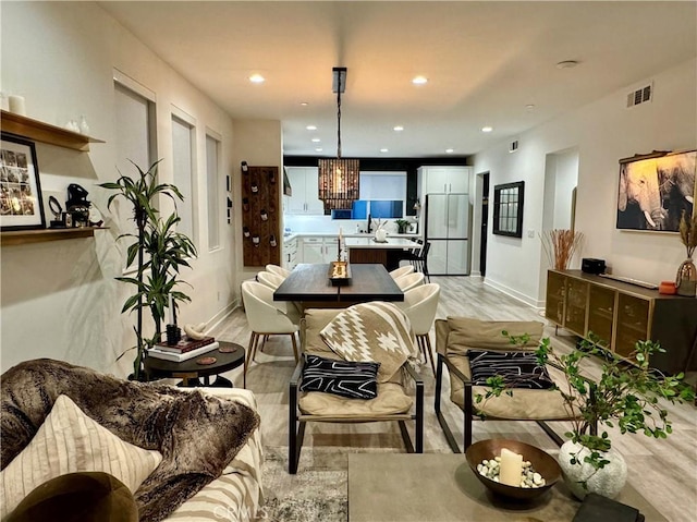 interior space with a chandelier, light wood-type flooring, white fridge, and pendant lighting