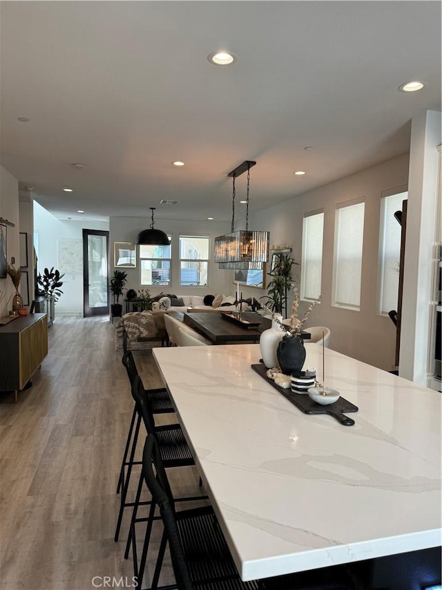 kitchen with a kitchen island, wood-type flooring, hanging light fixtures, a chandelier, and a breakfast bar area