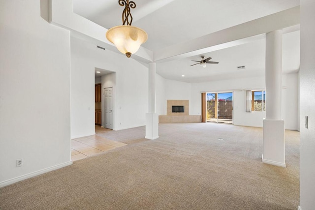 unfurnished living room featuring ceiling fan, light colored carpet, and a tile fireplace