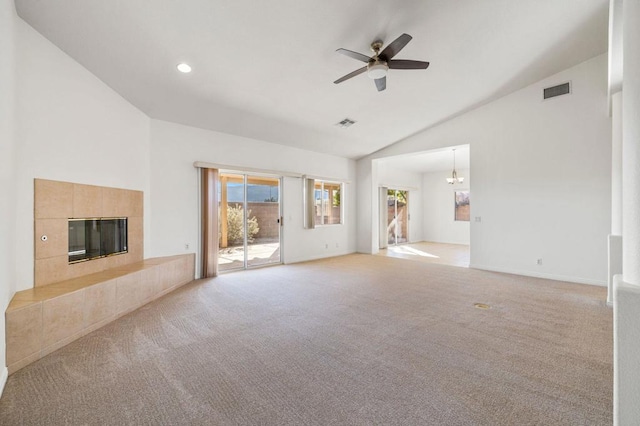 unfurnished living room with a tile fireplace, light carpet, ceiling fan with notable chandelier, and lofted ceiling