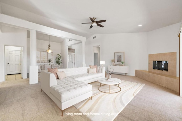 carpeted living room with ceiling fan and vaulted ceiling