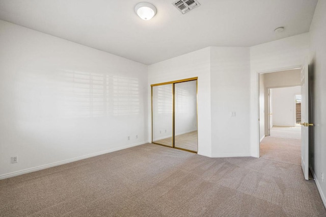 unfurnished bedroom featuring a closet and light colored carpet