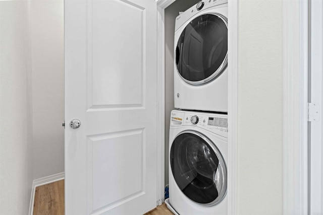 laundry room with stacked washer / dryer and light hardwood / wood-style floors