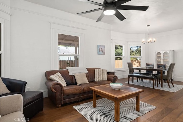 living room featuring ceiling fan with notable chandelier and dark wood-type flooring