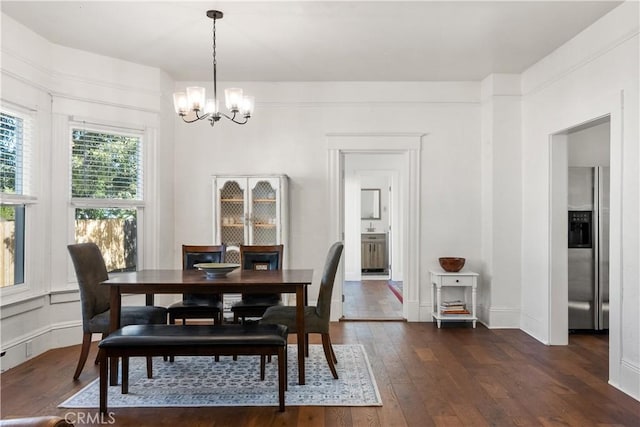 dining space featuring dark wood-type flooring and a notable chandelier