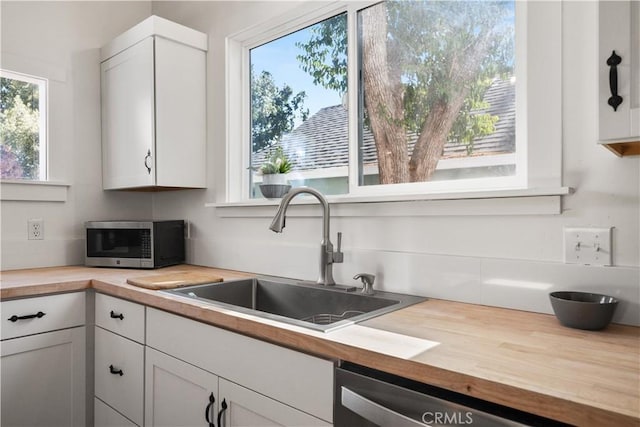 kitchen featuring white cabinets, butcher block counters, sink, and stainless steel appliances