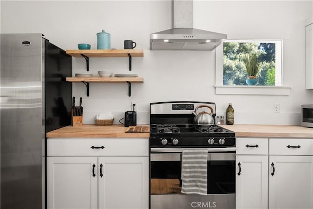 kitchen featuring wooden counters, stainless steel appliances, white cabinetry, and range hood