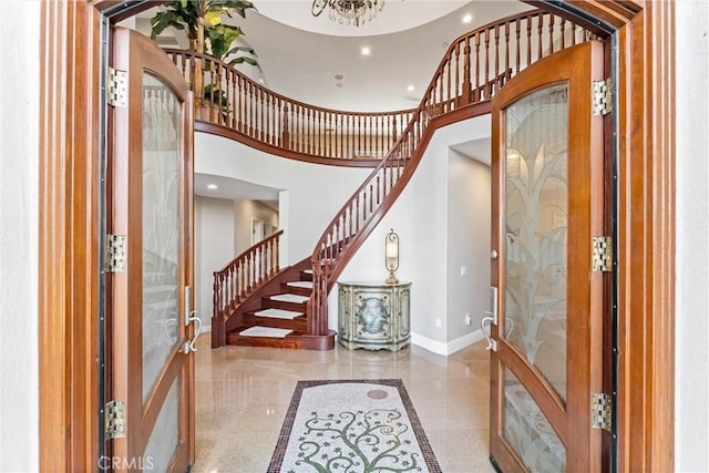 foyer entrance featuring an inviting chandelier, a high ceiling, and french doors