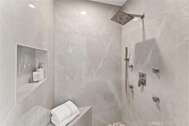 bathroom featuring a tile shower and tile walls