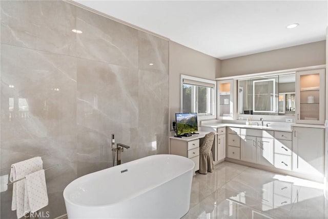 bathroom with a bathtub, tile walls, and vanity