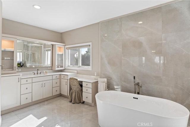 bathroom featuring vanity, a tub to relax in, and tile walls