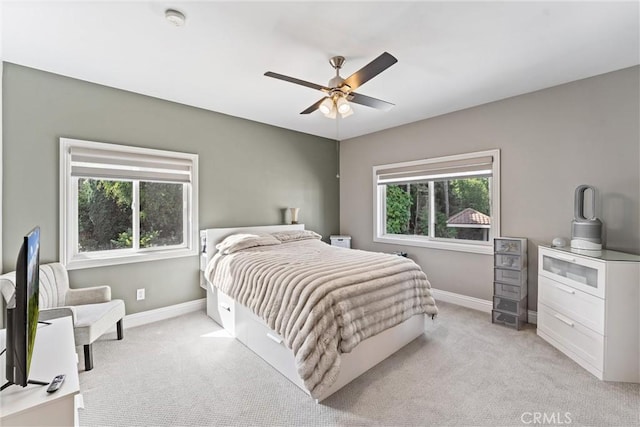 bedroom with multiple windows, light colored carpet, and ceiling fan