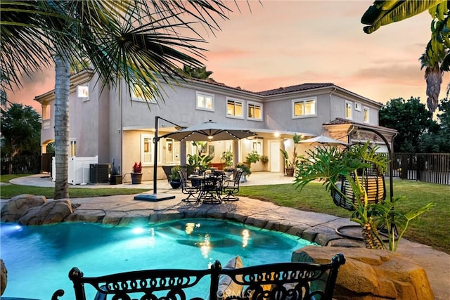 pool at dusk featuring central AC unit, a yard, and a patio