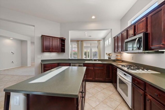 kitchen with light carpet, sink, a kitchen island, and appliances with stainless steel finishes