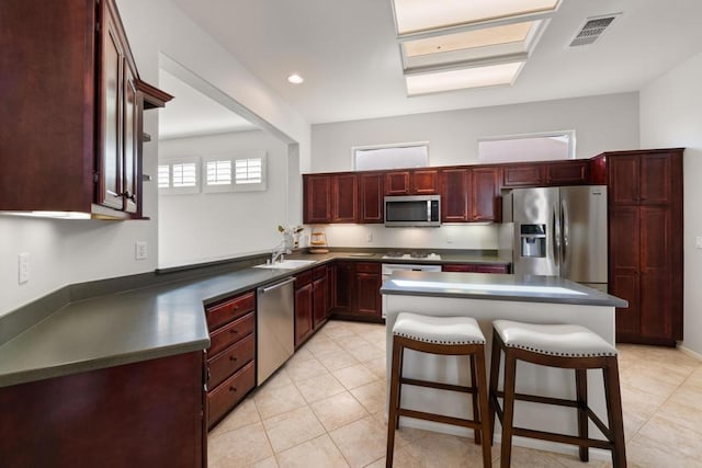 kitchen with light tile patterned flooring, appliances with stainless steel finishes, a kitchen bar, and sink