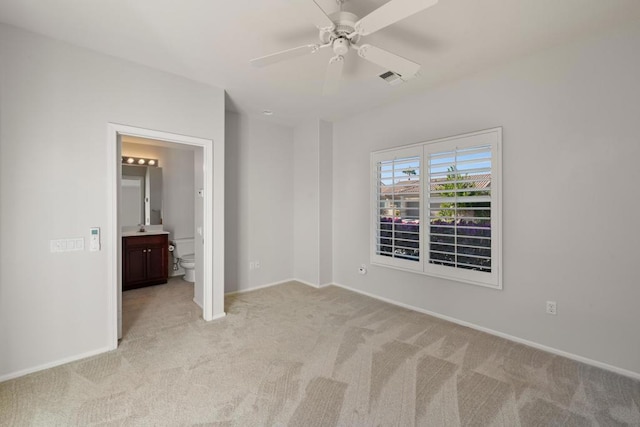 unfurnished bedroom with light carpet, ensuite bathroom, ceiling fan, and sink