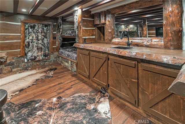 bar featuring dark hardwood / wood-style floors, beam ceiling, and sink