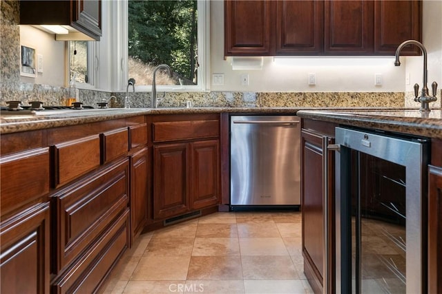 kitchen with dark stone counters, wine cooler, stainless steel dishwasher, and sink