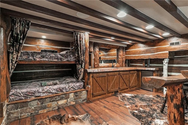 interior space featuring beamed ceiling, hardwood / wood-style flooring, black fridge, and sink