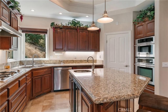 kitchen with a kitchen island with sink, sink, stainless steel appliances, and decorative light fixtures