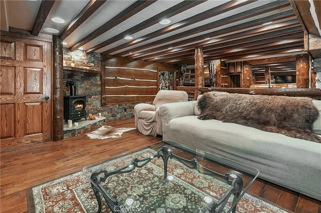 living room with beamed ceiling, wood-type flooring, and a wood stove