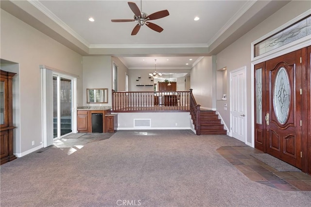 entryway featuring ceiling fan with notable chandelier, dark carpet, and ornamental molding