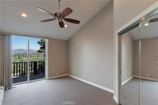 unfurnished room featuring a mountain view, carpet flooring, vaulted ceiling, and ceiling fan