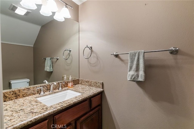 bathroom with vanity, toilet, and vaulted ceiling