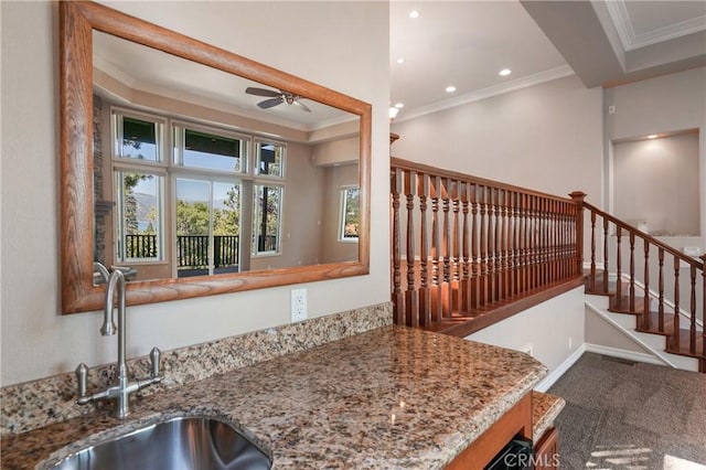 kitchen with carpet flooring, light stone counters, ceiling fan, crown molding, and sink