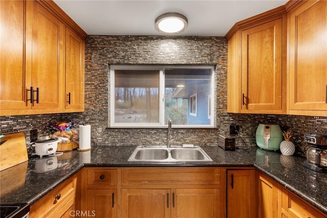 kitchen featuring tasteful backsplash, black range oven, dark stone counters, and sink