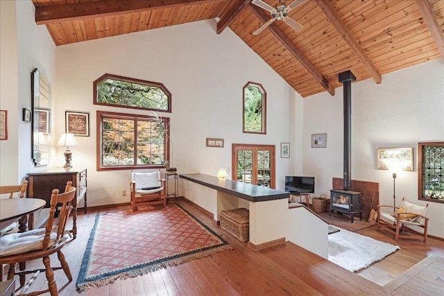 office space with french doors, wood ceiling, light wood-type flooring, a wood stove, and beam ceiling