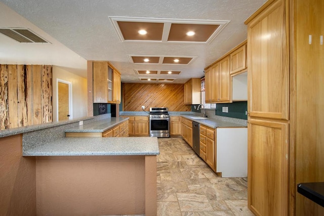 kitchen with sink, stainless steel appliances, light stone counters, kitchen peninsula, and a textured ceiling