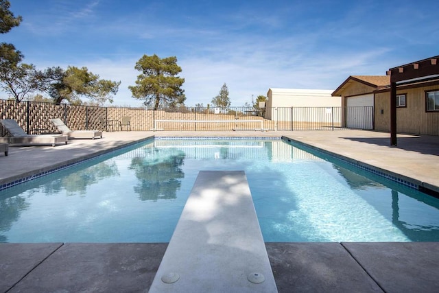 view of swimming pool featuring a diving board and a patio