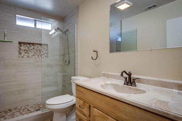 bathroom featuring a tile shower, vanity, wood-type flooring, and toilet