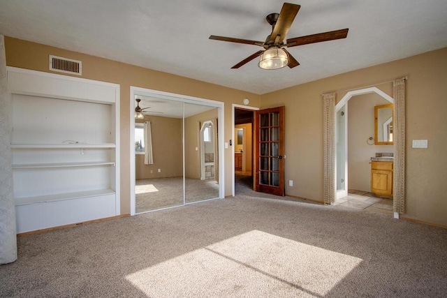 unfurnished bedroom featuring ceiling fan, light colored carpet, and a closet