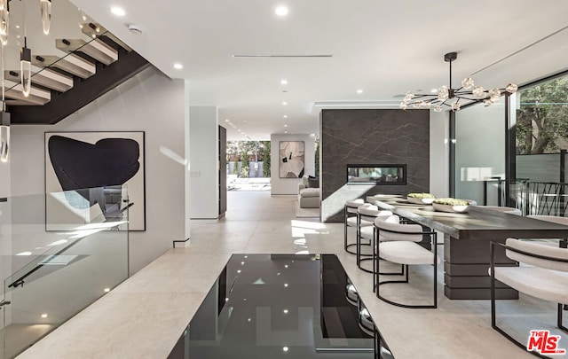 dining space with a healthy amount of sunlight, a wall of windows, a high end fireplace, and a chandelier