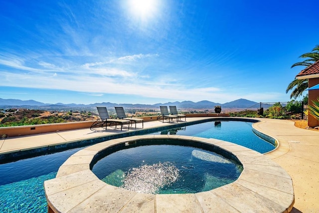 view of swimming pool with a mountain view, a patio area, and an in ground hot tub