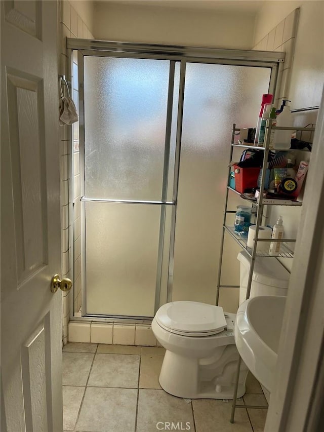 bathroom featuring tile patterned floors, a shower with door, and toilet