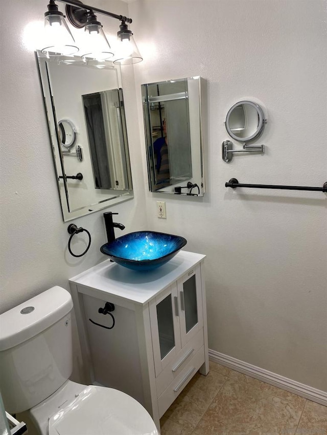 bathroom with toilet, vanity, and tile patterned floors